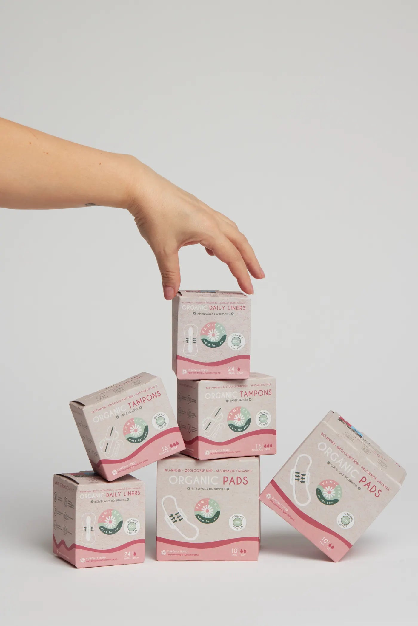 Schachteln mit Femieko Binden, Tampons und Slipeinlagen, zu einer Produktkomposition gestapelt
